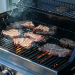 Summer Cedar Juicy steaks sizzle on a flaming gas grill, promising a delicious barbecue feast. summercedar.com