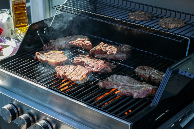 Summer Cedar Juicy steaks sizzle on a flaming gas grill, promising a delicious barbecue feast. summercedar.com