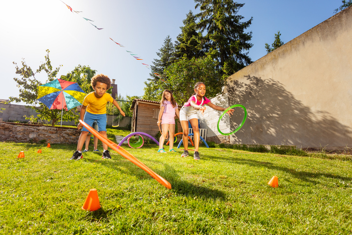 Family playing backyard games like cornhole, bocce, and croquet on a sunny afternoon
