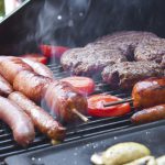 Burgers, brats, sausage, and vegetables on a grill for a backyard barbecue.