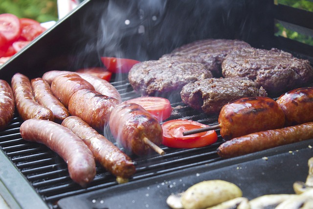 Burgers, brats, sausage, and vegetables on a grill for a backyard barbecue.